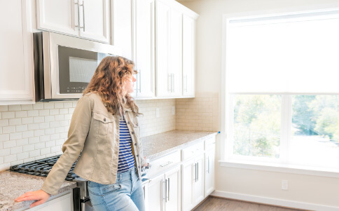 one young woman standing in kitchen in clean modern white home design before move in