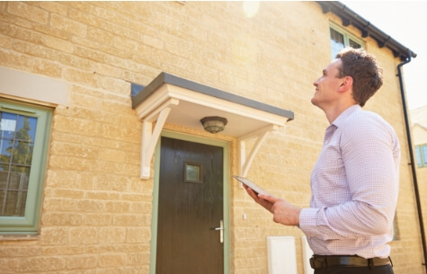 male real estate agent looking up at a house exterior